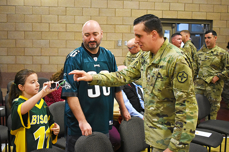 Army Sgt. Bill Daniels talks to children and family members after a farewell ceremony