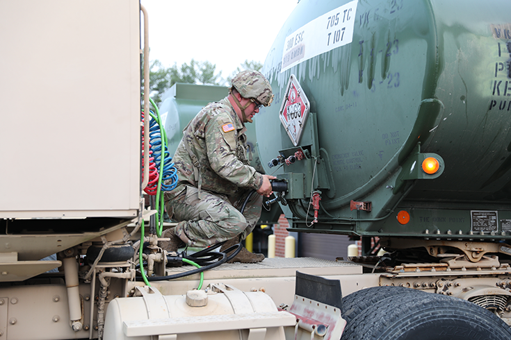 A horizontal photograph shows a helmeted Soldier kneeling to operate a fuel tank on a convoy vehicle.