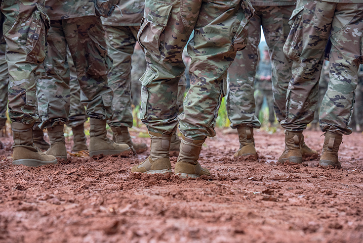 In the lead image for this article, a photograph shows the uniformed legs and boots of some half dozen Soldiers, standing together in red mud.