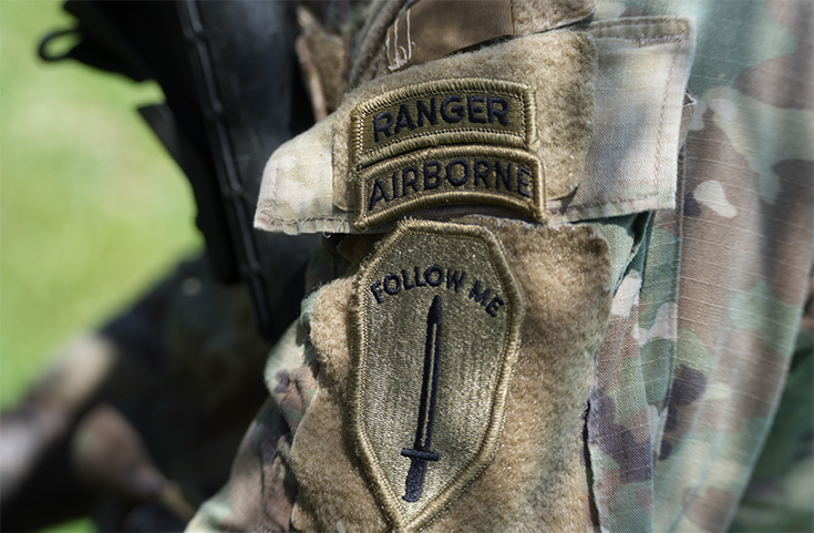 A close-up photograph shows the patches on a Soldier’s uniform. One says, “Ranger Airborne.” Below it, the other shows a sword beneath the legend, 'Follow Me.''