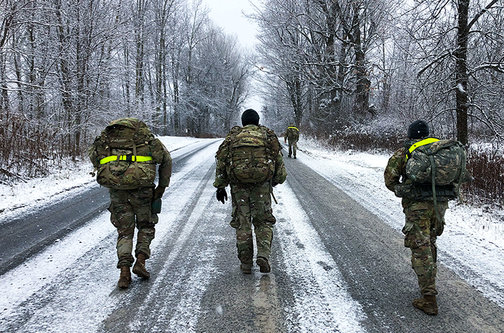 This lead image for the article shows a photo of the three Soldiers walking down a snow-covered road, with large packs upon their backs. This image is the first in a series of two accompanying the article.