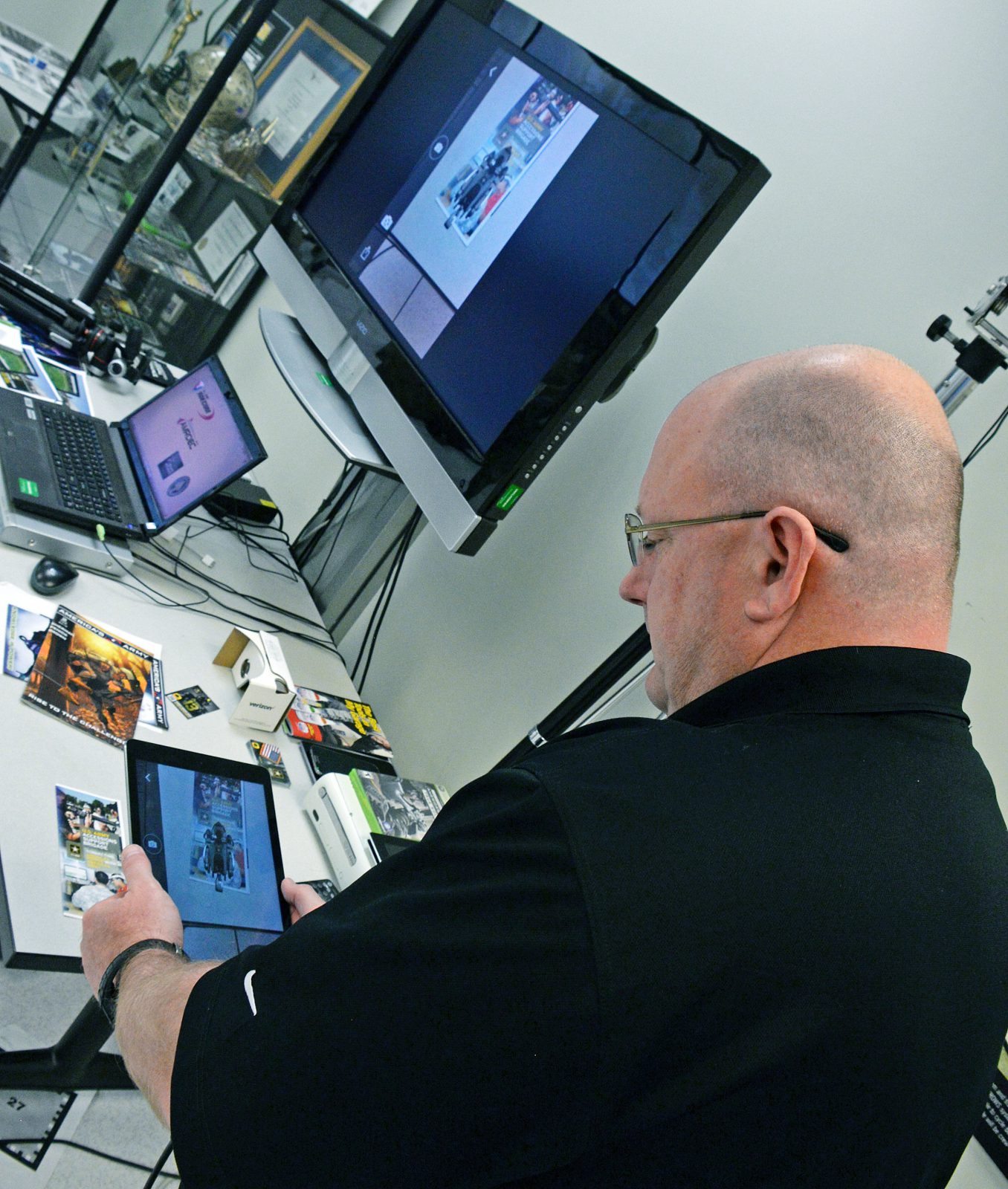 Jeff Sallas, software engineer test lead and support, demonstrates augmented reality technology at the Army Game Studio at Redstone Arsenal, Alabama. Augmented reality places images and effects on physical items such as brochures when they are viewed through an application. [Photo by Clifford Kyle Jones / NCO Journal]