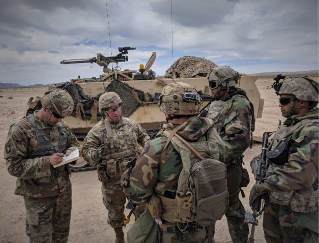 A team briefs Brig. Gen. Richard K. Sele (second from left), deputy commanding general, U.S. Army Civil Affairs and Psychological Operations Command (Airborne), on their operations in support of a brigade combat team at the National Training Center while Master Sgt. Kevin S. Williams (left), G7 Training Directorate NCOIC, USACAPOC (A), records his observations. (U.S. Army photo by 1st Lt. David W. Cline)