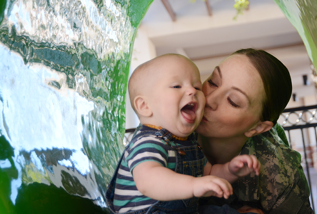 Spc. DeAmbra Meyer of Intelligence and Sustainment Company, Headquarters and Headquarters Battalion, 1st Armored Division plays with her 11-month-old son, Noah, at Freedom Crossing, an outdoor shopping center at Fort Bliss, Texas. (Photo by Meghan Portillo / NCO Journal)