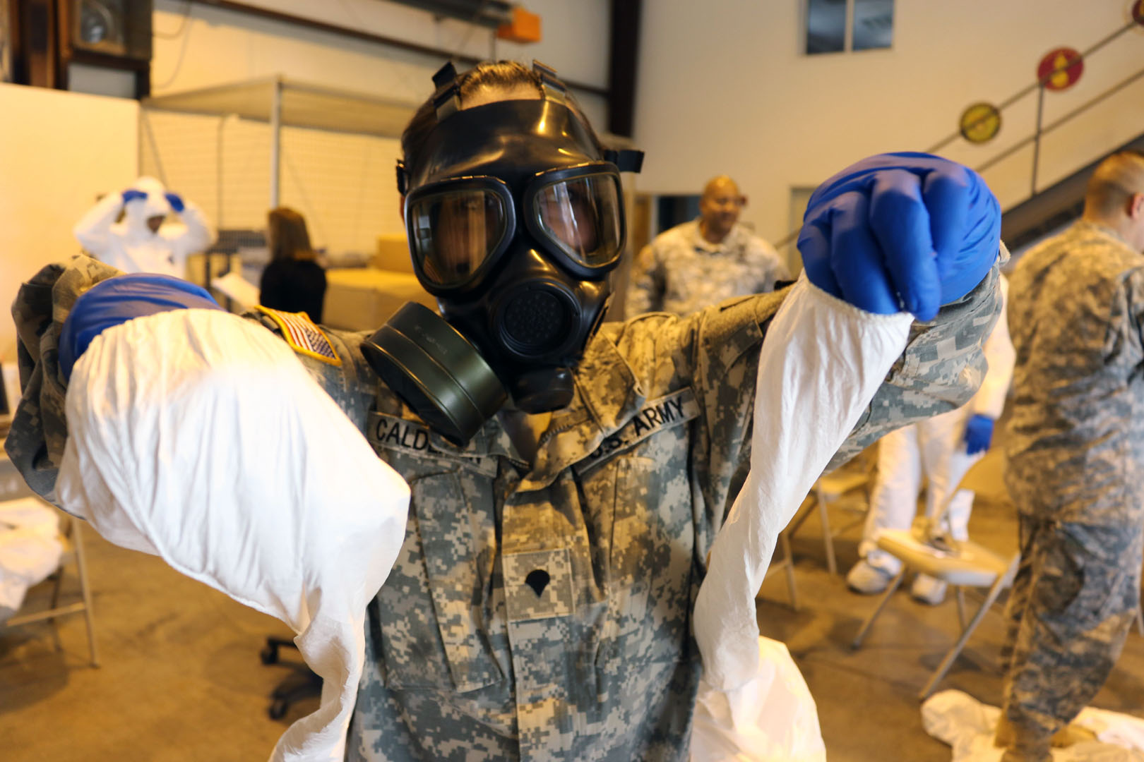 Spc. Kristal Calderon, an information technology support specialist with the 35th Signal Brigade (Theater Tactical) at Fort Gordon, Ga., practices carefully donning and removing personal protective equipment during pre-deployment training at the brigade’s logistical warehouse at Fort Gordon. The training was mandatory for the Soldiers who deployed to Liberia in late October to add their communications equipment and expertise to the fight against the Ebola outbreak in West Africa. (Photo by Capt. Lindsay D. Roman/U.S. Army)
