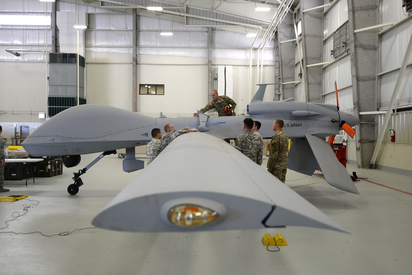 Sgt. Will Scott (top) and other unmanned aircraft systems repairers perform a preflight weight and balance check on a Gray Eagle UAV. (Photo by Meghan Portillo/NCO Journal)